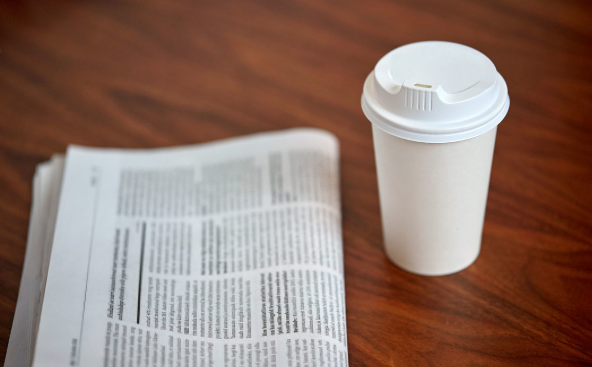 coffee drink in paper cup and newspaper on table